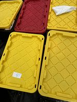 Photo of four plastic storage tote lids, mostly yellow with one red, labeled with numbers 6 and 9 on taped paper.
