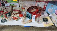 Wide view of Christmas and baking related items showing table runner, baking utensils, ornaments, and glassware arranged on a shelf.