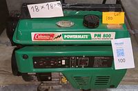 Front and top view of green Coleman Powermate PM 800 showing fuel cap, metal housing, branding and lot label