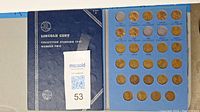 Blue coin holder album open showing Lincoln cents in individual slots marked for years starting 1941.