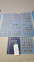 Six blue cardboard coin holder boards arranged with Lincoln Head Cent coins from 1909 to 1940, along with the blue folder cover.