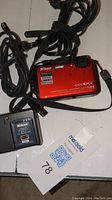 Top view of red Nikon Coolpix camera with charger and USB cable
