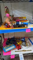 Photo showing assorted antique items on shelves including toys, binoculars, watches, typewriter, and various collectibles
