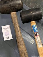 Two rubber mallets, one used and one new, placed on a table next to a MaxSold lot card.