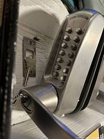 Close-up of Codelock keypad door lock with lever handle installed on a door, includes two keys in lock cylinder.