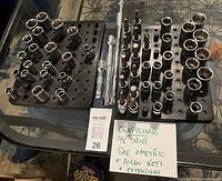 Photo of the Craftsman 3/8 drive sockets in SAE and metric sizes along with Allen key sockets and three extensions arranged neatly in two black socket trays on a glass table.