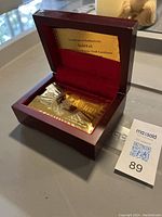Open wooden box displaying gold foil playing cards and certificate of authenticity inside with velvet lining.