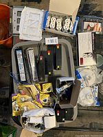 Photo showing multiple white duplex receptacles, wall plates, some yellow packaged items, black batteries, and ballasts.