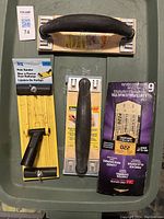 Photo showing three sanding tools and sandpaper sheets lying on a surface.