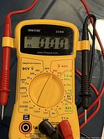 Front view of the yellow Innova 3300 digital multimeter showing LCD screen with TEST MODE reading and multimeter rotary dial with test lead ports and attached probes.