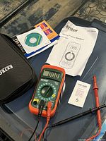 Photo showing the Extech multimeter with screen, test leads plugged in, instruction manual, CD, and carrying case.