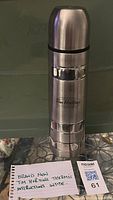Photo shows stainless steel Tim Hortons thermos standing upright and a small note indicating new condition and instructions included.