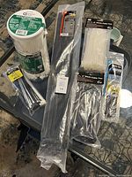 Top-down photo showing seven packages of nylon zip ties in varying lengths and colors spread on a glass table.