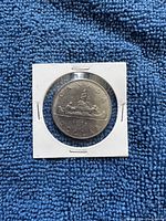 Reverse side of the 1975 Canadian dollar coin showing the Voyageur design with a canoe and Northern Lights.