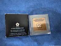 Official Expo 70 commemorative copper medal in protective casing alongside original black storage box with Expo 70 and multilingual text.