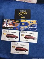 Six old calling cards arranged on a blue cloth including Walmart, TELUS, Landmark Extras, and three Focus cards.