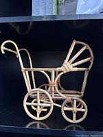 Front and side views of the vintage rattan baby carriage plant basket holder showing intricate woven rattan design and four wheels.