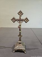 Front view of the antique metal crucifix showing detailed Christ figure and ornamental ends.