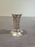 Side view of antique silver vase showing octagonal base and vertically fluted body