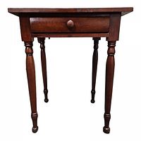 Front view of antique wooden side table showing single drawer with round wooden knob and four turned legs.