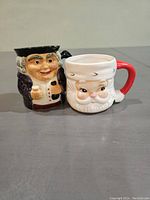 Two character mugs: a historical figure mug and a smiling Santa mug with a red handle