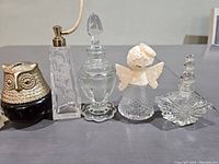 Photo showing six vintage perfume bottles on a flat surface, highlighting their shapes and gold accents.