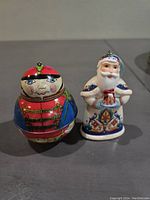Front view of both ornaments: colorful tin nutcracker soldier and ceramic Russian-style Santa Claus