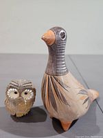 Front view of the small owl figurine next to the larger dove figurine showing painted details and carved textures