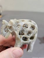 Close-up front side view of the hand-carved stone elephant figurine showing the detailed openwork design revealing an inner smaller elephant inside the hollow body.