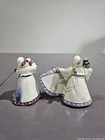 Back view of two Santa Claus figurine ornaments showing plain white and blue back of robes with minimal decoration.