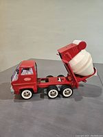 Side view of the Tonka vintage cement mixer truck showing red metal body, white wheels, and the tilted white cement mixer drum.