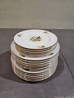 Stacked view of the dinnerware set showing the plates and bowls with yellow rose patterns and gold rim.