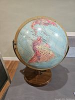 Front view of vintage globe showing South America, mounted on wood-effect round base with metal meridian.