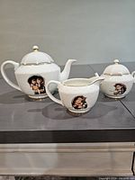 Full set showing teapot, creamer, and sugar bowl with Umbrella Boy & Girl illustrations and gold detailing.