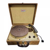 Full view of open vintage Symphonette record player showing felt turntable platter, tonearm, control knobs, handle, and textured case interior lid with label.
