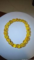 Front view of chunky Baltic amber bracelet laid flat in circular shape showing smooth polished oval golden amber beads.