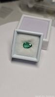 Pear cut emerald in white display box viewed from above