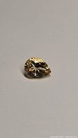 Single pear shaped natural golden citrine gemstone on plain light background, showing facets and clarity in natural lighting.