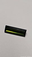 Top view of natural green tourmaline baguette cut gemstone showing its shape, color, and polished facets.