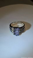 Front view showing the three oval tanzanite stones on the sterling silver band with clear accent stones on the sides