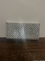 Front view of the silver studded clutch bag showing the geometric studded texture.