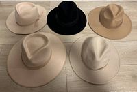 Top view of all five fedora hats in a variety of neutral colors arranged on the floor.