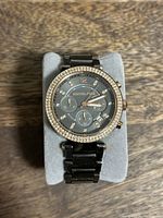 Front view of Michael Kors black watch with crystal bezel and chronograph subdials on black dial.