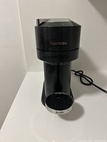 Front view of the black Nespresso Vertuo Next coffee and espresso machine showing the Nespresso logo and the metal 'Breville' branded drip tray.