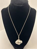 Full view of silver fish pendant hanging on a fine silver chain displayed on black necklace bust.