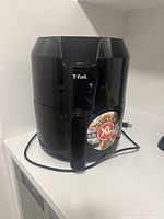 Front view of black Tefal XL air fryer with 4.2 litre capacity label and power cord visible.