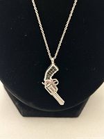 Close-up of sterling silver pistol-shaped pendant showing black gemstone insets.