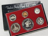 Photo of the 1976 United States Mint Proof Set with six proof coins displayed in red insert and black cardboard folder showing some wear.