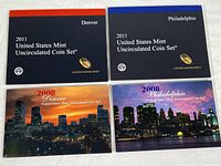 Front covers of four coin set folders: 2011 Denver, 2011 Philadelphia, 2008 Denver, 2008 Philadelphia with city skyline images on 2008 sets.