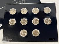 Set of 10 uncirculated 2011 America the Beautiful quarter coins displayed on black card packaging with clear pockets showing obverse and reverse designs.